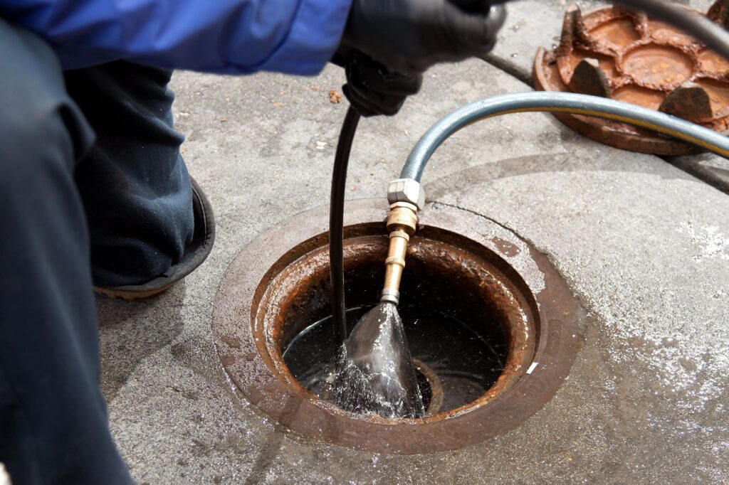 Plumber hydro jetting a sewer line through a manhole in Bethel Park