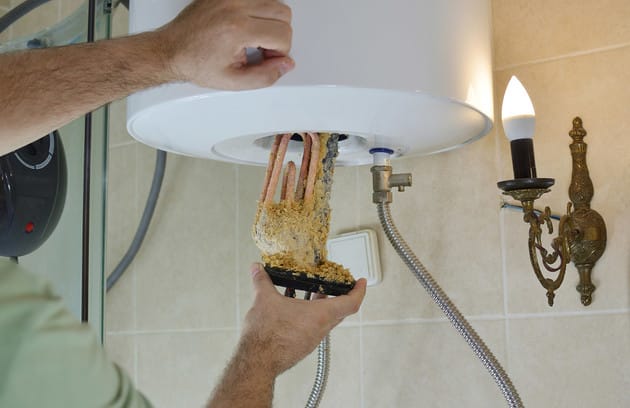 Technician removing mineral buildup from a water heater in Bethel Park