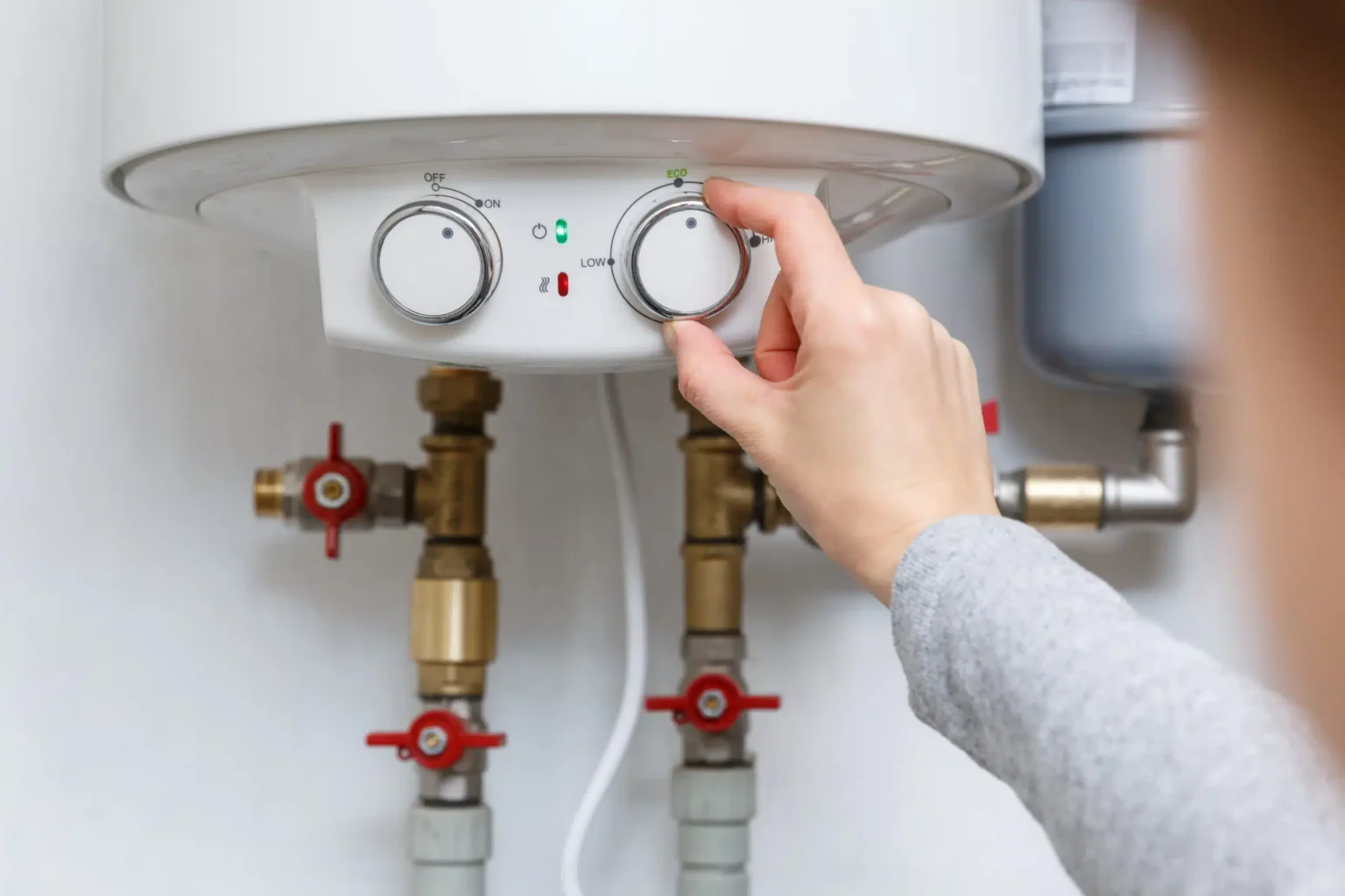 Homeowner adjusting the temperature controls on a water heater in Bethel Park